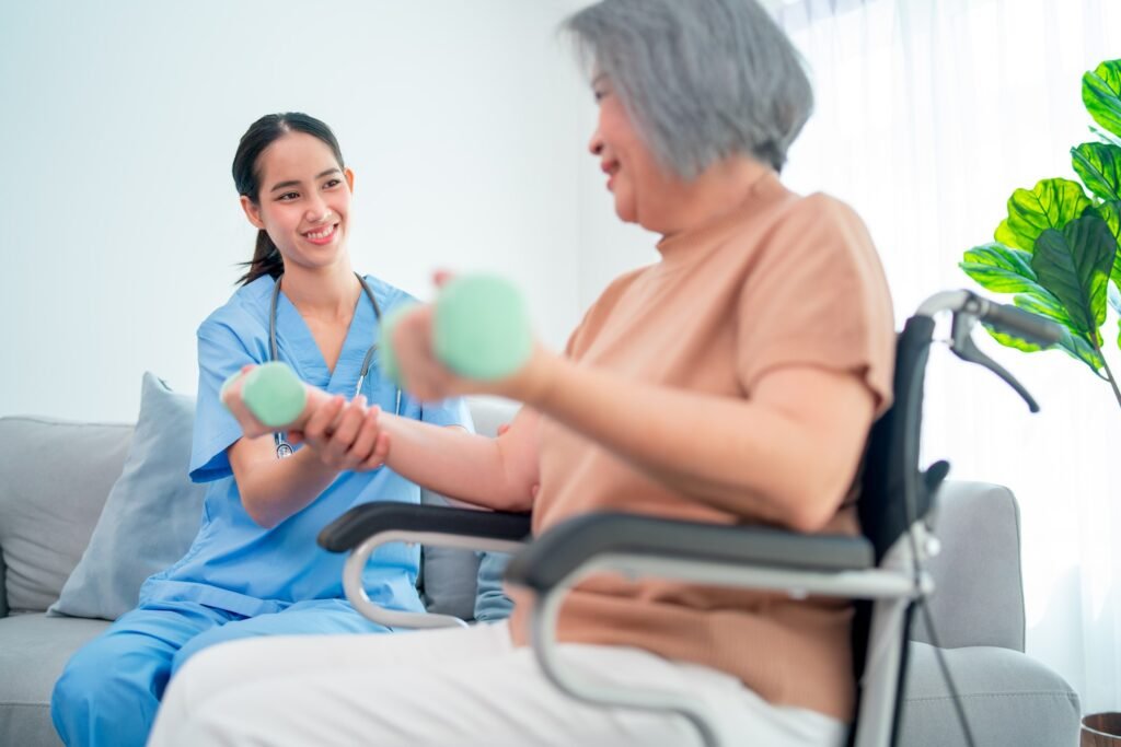 Asian young nurse help and support elderly or senior woman to exercise with dumpbell in living room