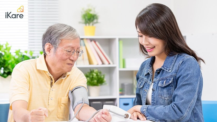 Female caretaker measuring senior man’s blood pressure at home