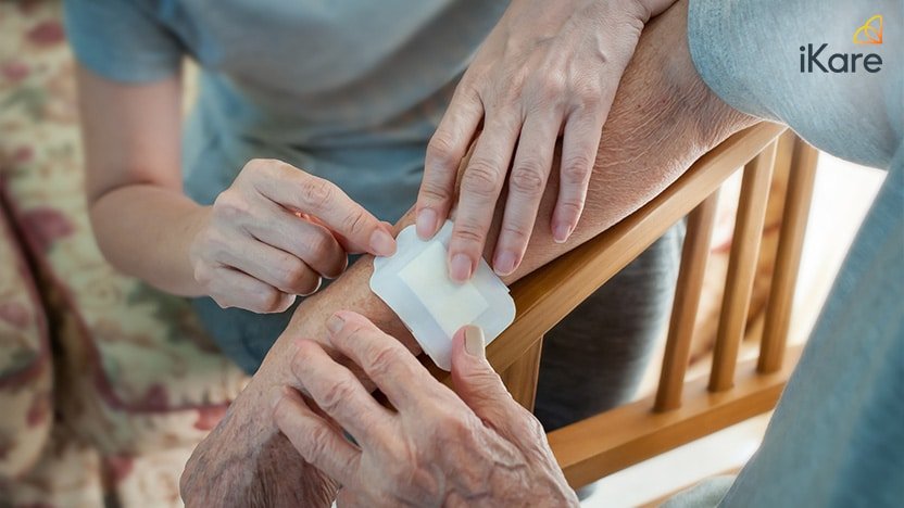 Close up of putting the medical plaster on senior adult’s hand