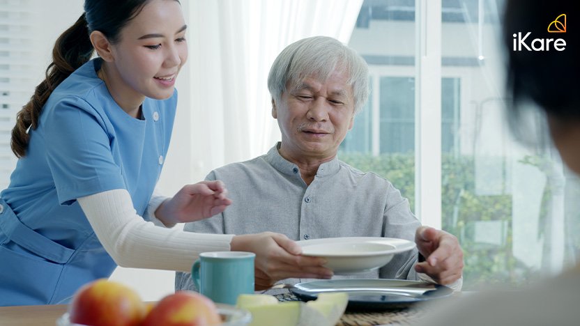 Senior couple eating healthy breakfast meal on dining table with the assist of nurse
